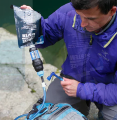 a photo of a man using the sawyer fast fill adapters for hydration packs