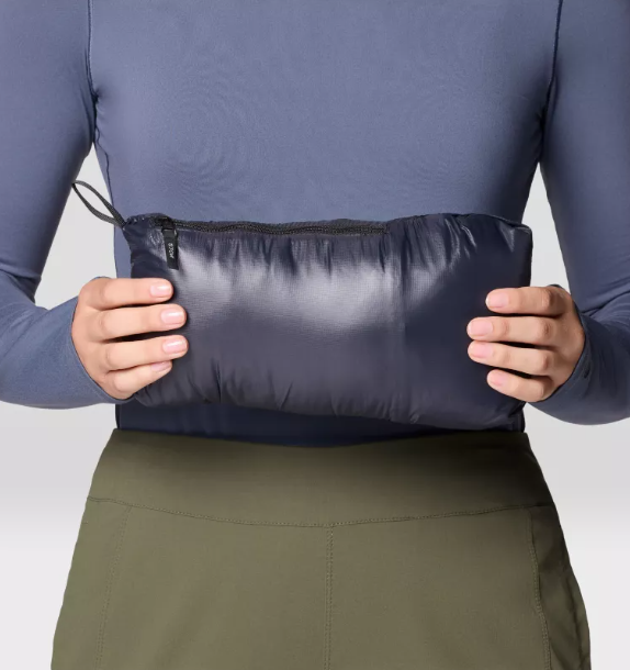 person holding a mountain hardwear ghost shadow jacket womens in black stuffed into its pocket