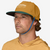 the patagonia merganzer hat in the color water people pufferfish gold, front view on a model showing the elastic chin strap in use