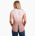 a model wearing the kuhl womens isla short sleeve shirt in the color sand, back view
