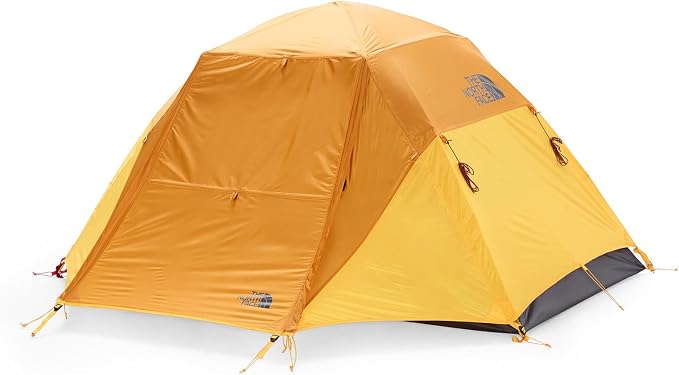 A yellow and orange dome camping tent with a gray rainfly hem, shown on a clean white background. The brand logo for The North Face is visible on the upper right side.