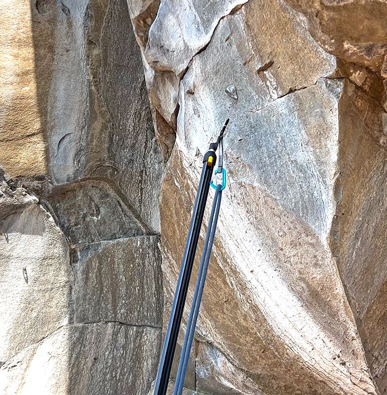 a photo of the metolius superclip on the end of a pole, being used to clip a bolt
