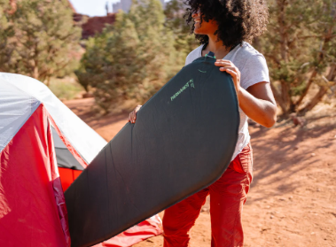 a woman pulling a thermarest trail scout out of a tent