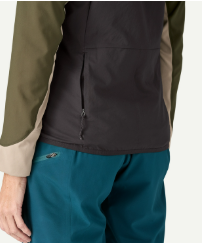 Close-up of a person wearing a dark charcoal zip-front vest or jacket with olive green and beige sleeves, paired with teal pants.