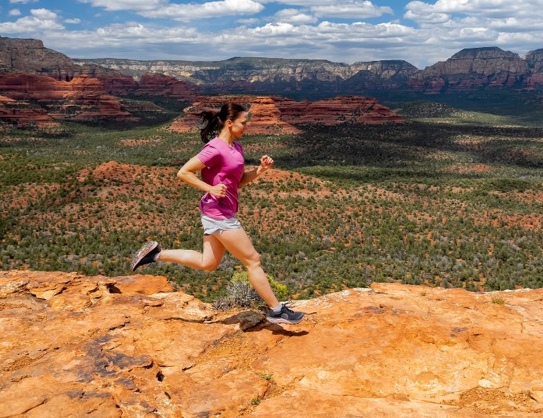 a photo of the topo mountain racer 3 running shoe in the color black/mauve, view of a model running through the desert