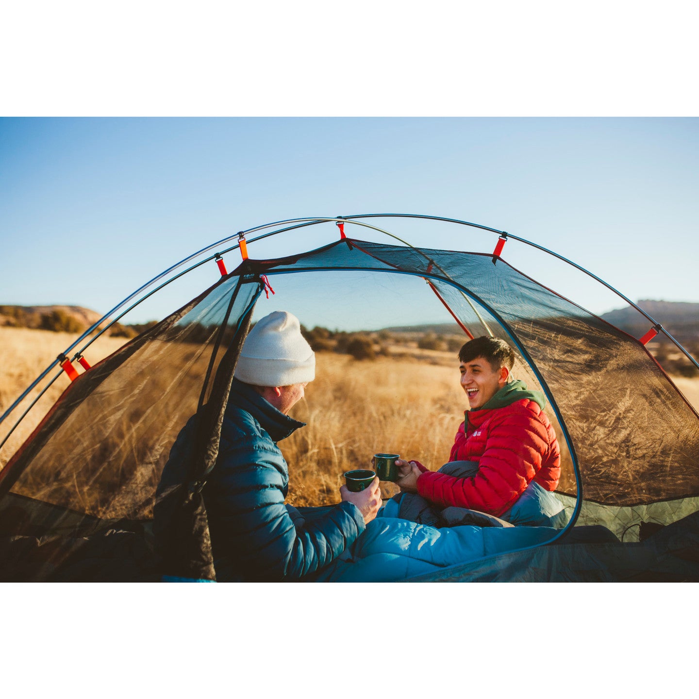 lifestyle image showing two people in a tent sitting up in their sleeping bags