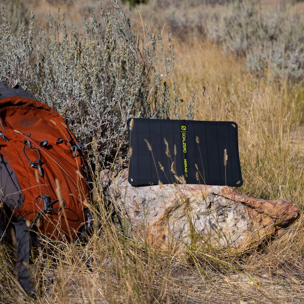 a nomad 10 is open on a rock with an orange backpack next to it 