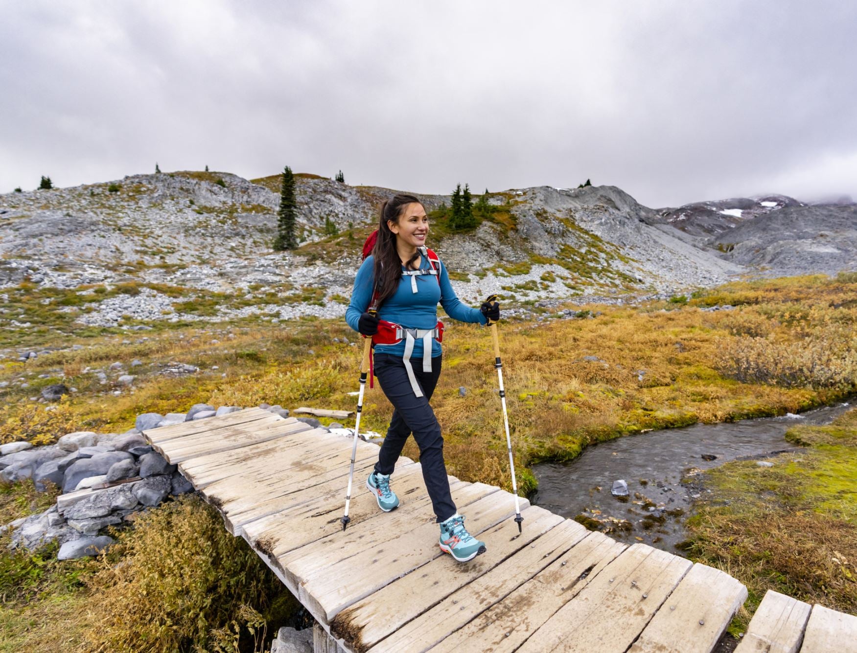 photo of a woman walking in the womens topo trailventure 2 in teal/coral