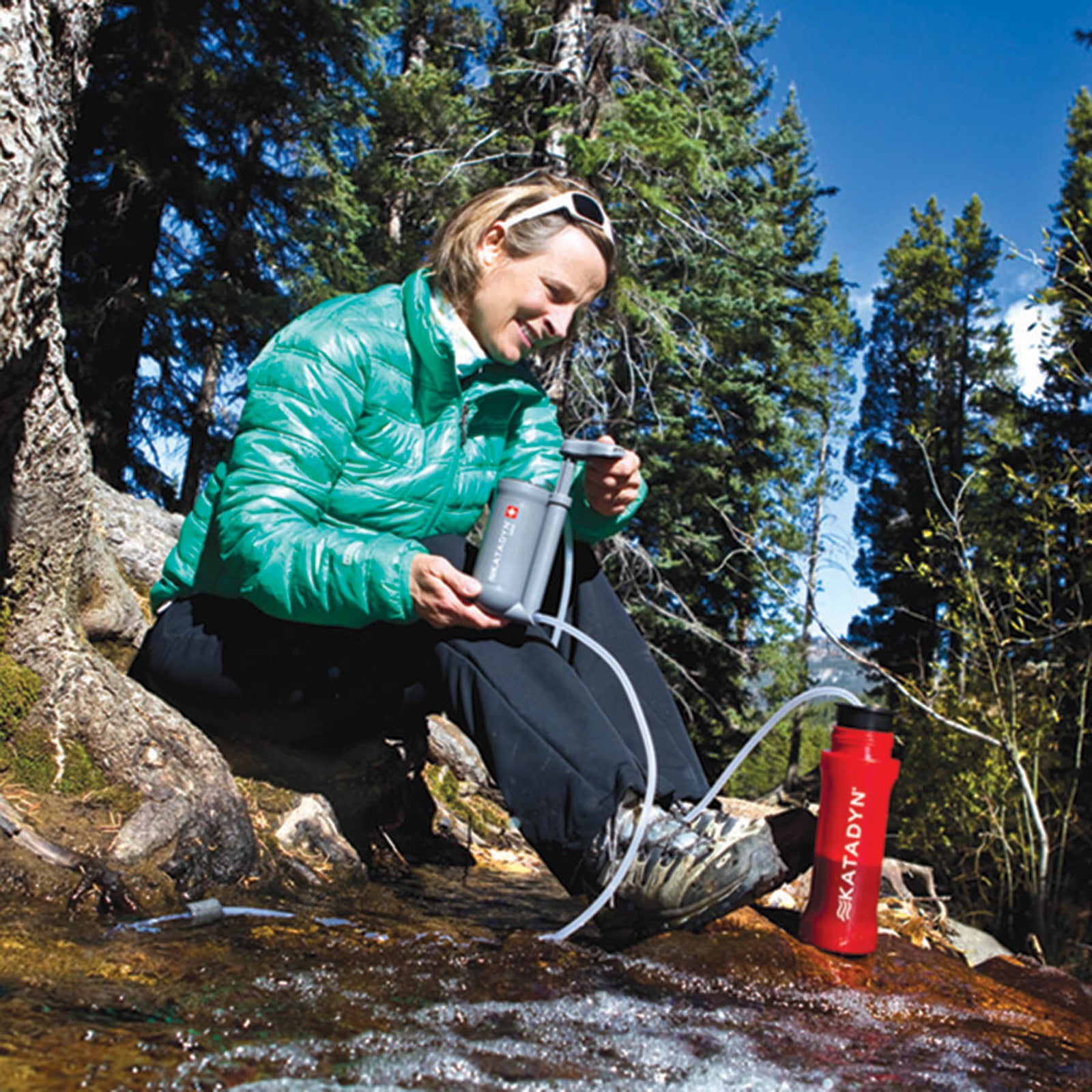 a women using the water filter at a creek